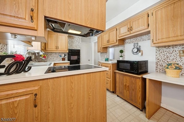 kitchen with light floors, under cabinet range hood, a sink, light countertops, and black appliances