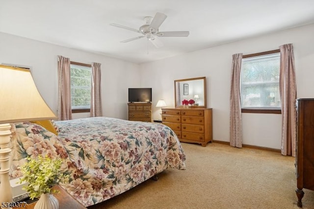 bedroom featuring a ceiling fan, light carpet, and baseboards