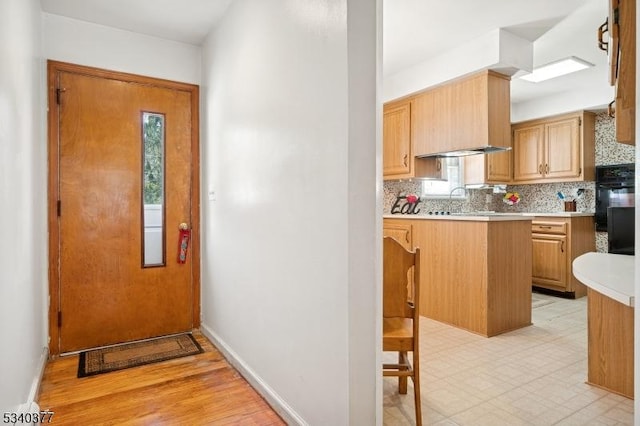 kitchen with a peninsula, baseboards, light countertops, decorative backsplash, and light floors