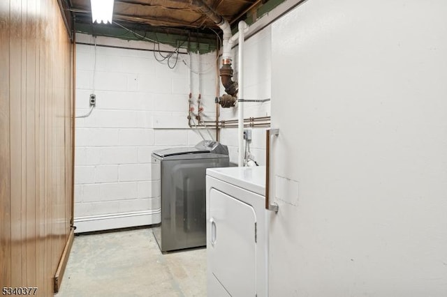 clothes washing area with concrete block wall, laundry area, and independent washer and dryer