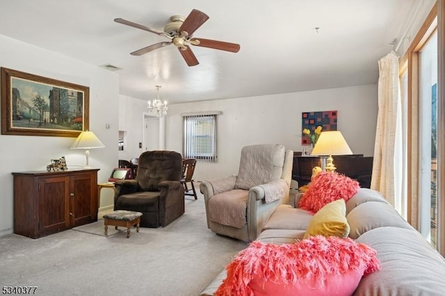 living area featuring light carpet, ceiling fan with notable chandelier, and visible vents