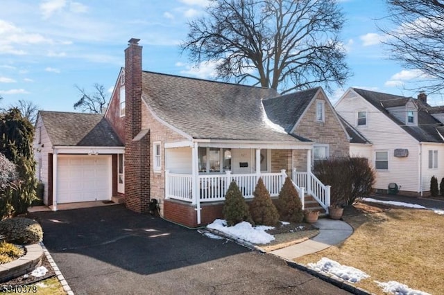 view of front of property with a porch, aphalt driveway, a garage, roof with shingles, and a chimney