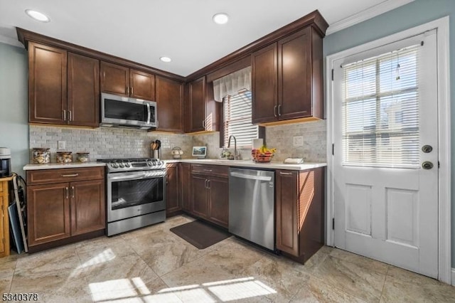 kitchen with stainless steel appliances, light countertops, decorative backsplash, dark brown cabinetry, and a sink