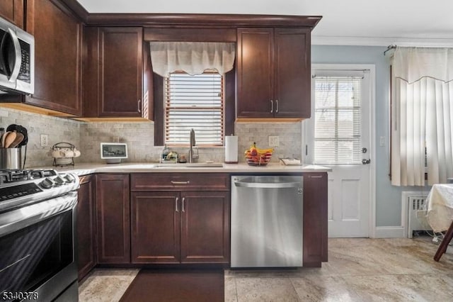 kitchen featuring a sink, light countertops, appliances with stainless steel finishes, tasteful backsplash, and crown molding