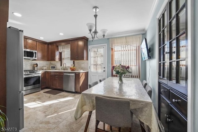 kitchen with decorative light fixtures, light countertops, decorative backsplash, appliances with stainless steel finishes, and a chandelier