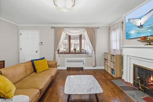 living room with radiator, crown molding, dark wood finished floors, and a tiled fireplace