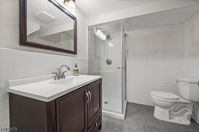 bathroom featuring toilet, vanity, tile walls, wainscoting, and a shower stall