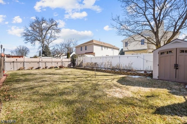 view of yard featuring a storage shed, a fenced backyard, and an outbuilding