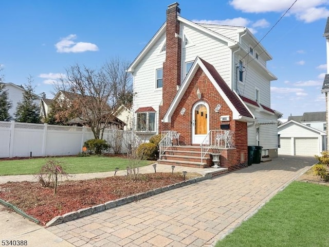 view of front of home featuring an outbuilding, brick siding, fence, a chimney, and a front yard