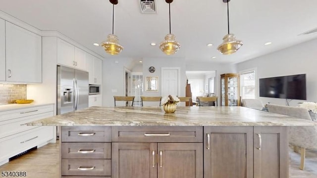 kitchen with visible vents, white cabinets, backsplash, and built in appliances