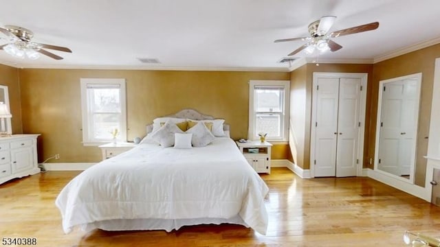 bedroom with ornamental molding, light wood-type flooring, visible vents, and baseboards