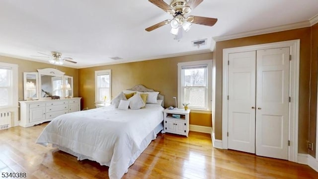 bedroom featuring radiator, light wood-style floors, visible vents, and crown molding