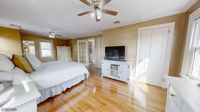 bedroom featuring visible vents, crown molding, light wood-style flooring, and ceiling fan