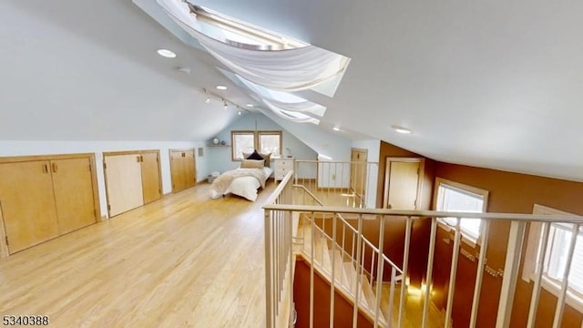 additional living space with lofted ceiling with skylight and light wood-style flooring