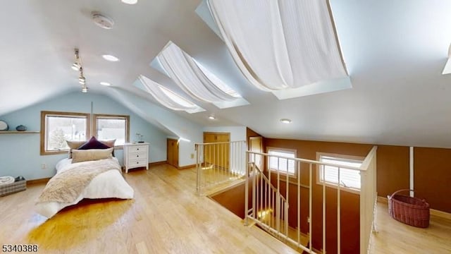 additional living space featuring a healthy amount of sunlight, lofted ceiling with skylight, and wood finished floors