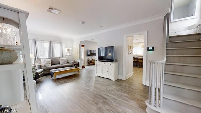 living room featuring visible vents, baseboards, stairway, wood finished floors, and crown molding