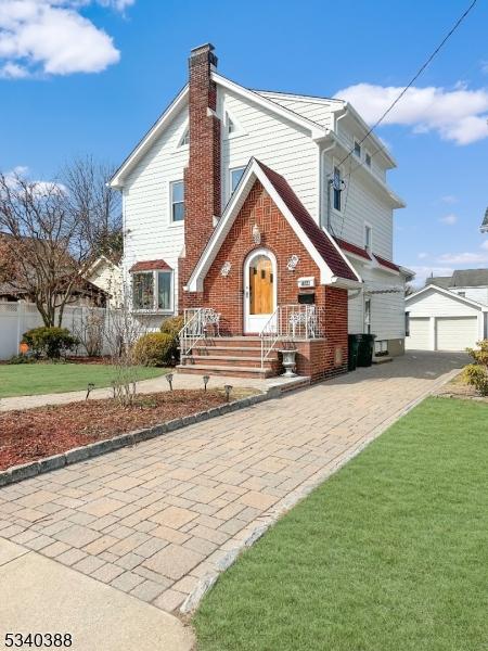 view of front of property with brick siding, an outdoor structure, a chimney, and a front lawn