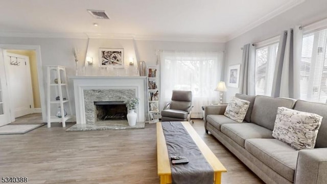 living room with a fireplace, wood finished floors, visible vents, and crown molding