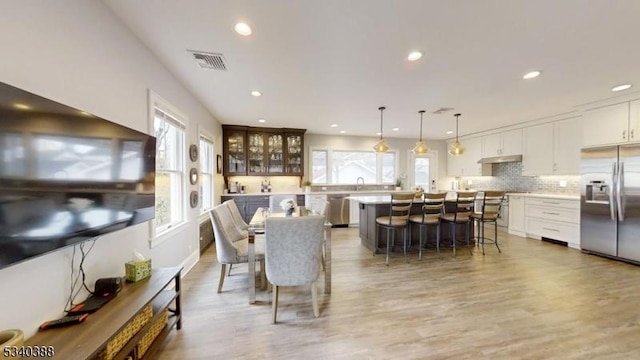 kitchen with a breakfast bar, a kitchen island, visible vents, white cabinetry, and appliances with stainless steel finishes