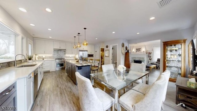 dining area with a healthy amount of sunlight, light wood-type flooring, a fireplace, and visible vents