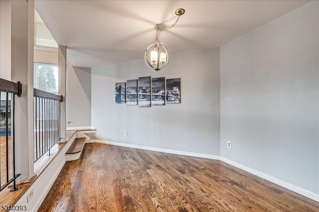 unfurnished dining area featuring a chandelier, wood finished floors, and baseboards