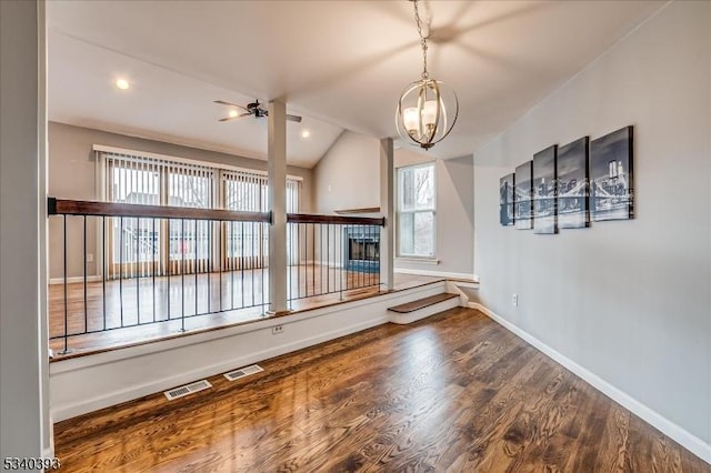 unfurnished living room featuring a wealth of natural light, lofted ceiling, baseboards, and wood finished floors