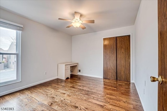 unfurnished bedroom featuring multiple windows, baseboards, and wood finished floors