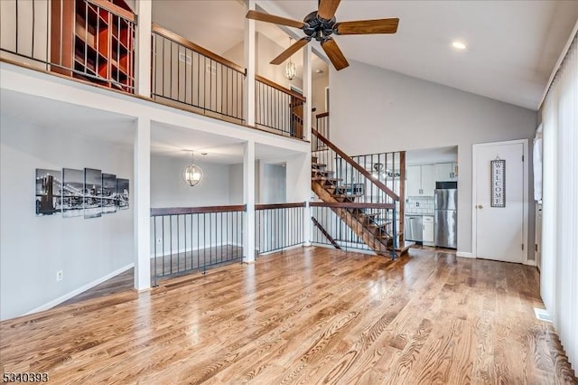 unfurnished living room with baseboards, wood finished floors, and ceiling fan with notable chandelier