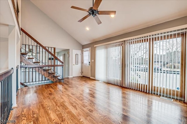 interior space with stairs, ceiling fan, high vaulted ceiling, and wood finished floors