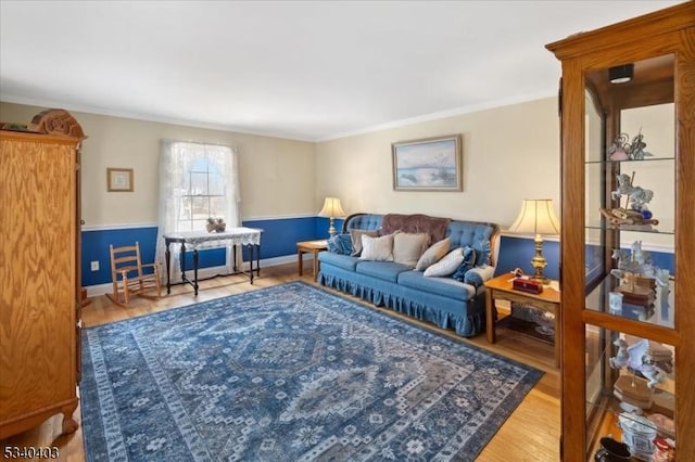living area with crown molding, baseboards, and wood finished floors