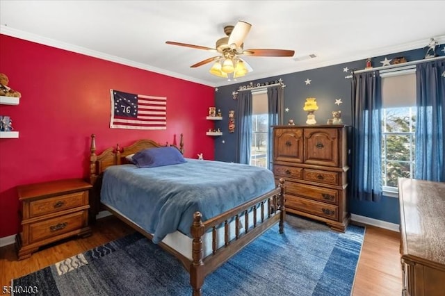 bedroom featuring baseboards, wood finished floors, and crown molding