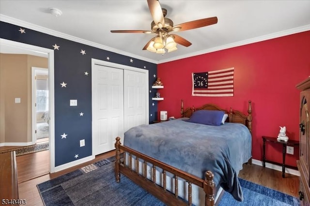 bedroom with ceiling fan, wood finished floors, baseboards, ornamental molding, and a closet
