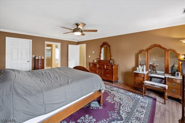 bedroom with crown molding, a ceiling fan, wood finished floors, and ensuite bathroom