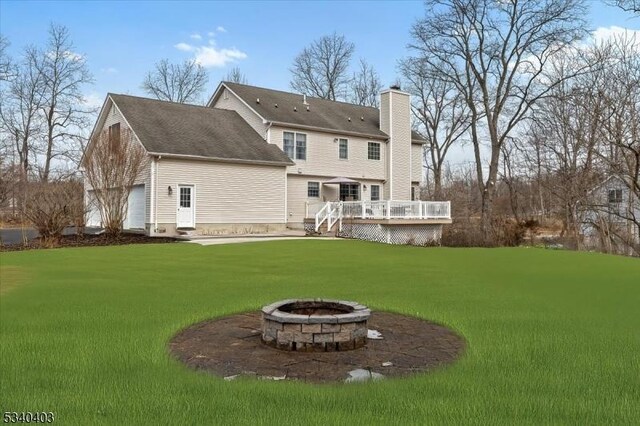 rear view of house with a yard, an outdoor fire pit, a chimney, and a wooden deck