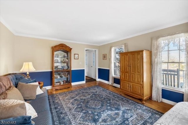 living area featuring crown molding, plenty of natural light, baseboards, and wood finished floors