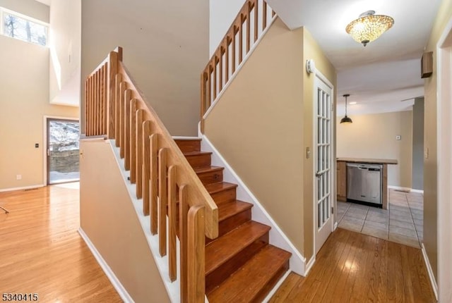 staircase featuring a high ceiling, wood finished floors, and baseboards