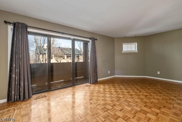 unfurnished room featuring visible vents, a wealth of natural light, and baseboards