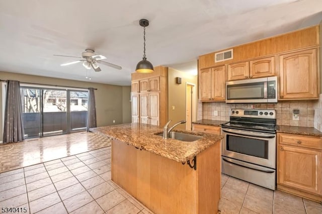 kitchen featuring stone counters, stainless steel appliances, a sink, visible vents, and decorative backsplash