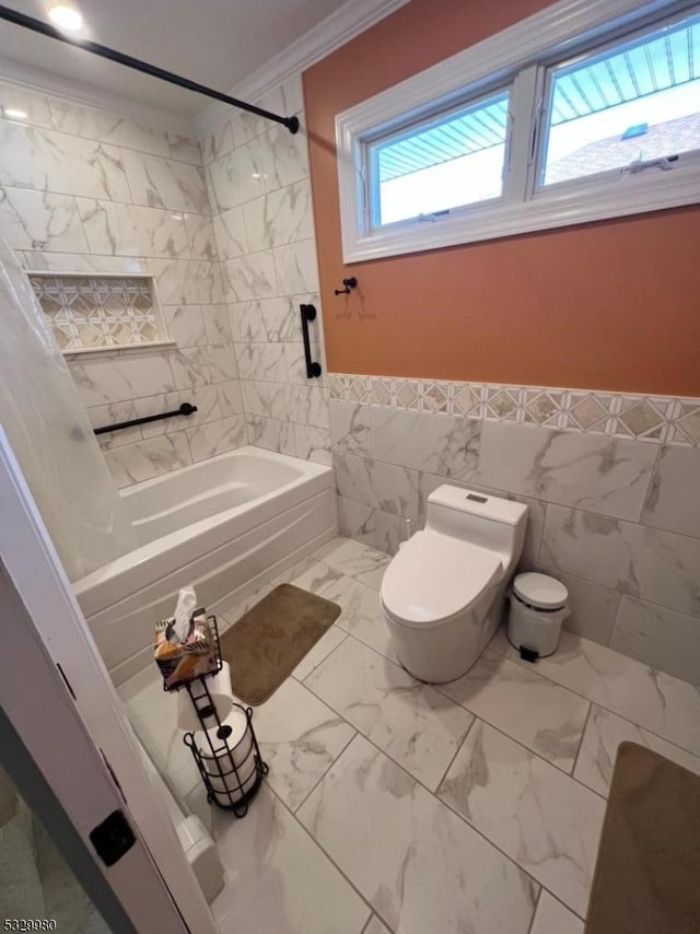 bathroom featuring toilet, a wainscoted wall, shower / tub combo, marble finish floor, and ornamental molding