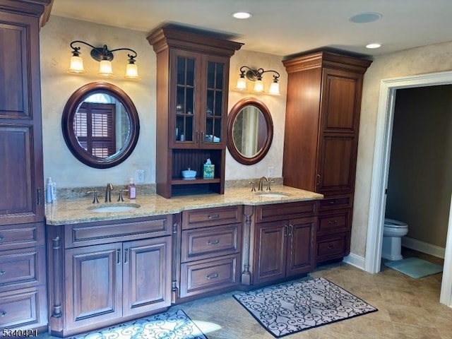 full bathroom with double vanity, a sink, toilet, and tile patterned floors