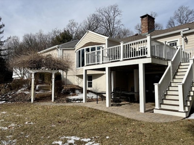 rear view of property with a chimney, a yard, a deck, and stairs