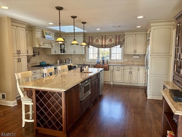 kitchen with pendant lighting, a breakfast bar area, cream cabinets, glass insert cabinets, and a kitchen island