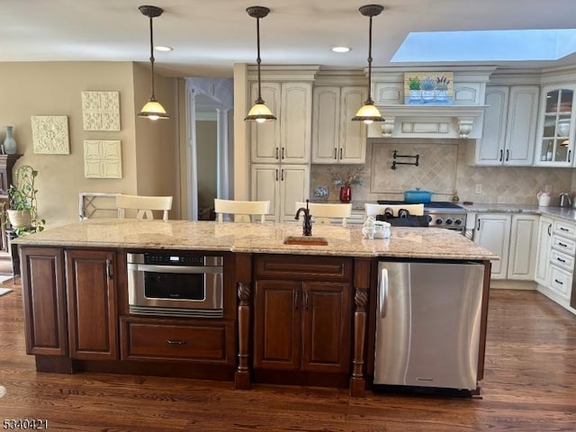 kitchen featuring white cabinets, appliances with stainless steel finishes, light stone countertops, glass insert cabinets, and pendant lighting