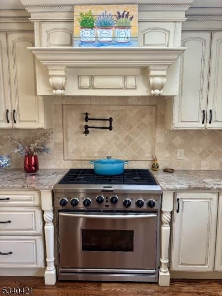 kitchen with tasteful backsplash, stainless steel range, and light stone countertops