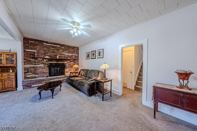 living room with light carpet, a brick fireplace, stairway, and a ceiling fan