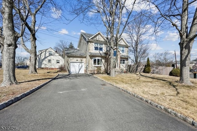 view of front of property featuring aphalt driveway, an attached garage, and fence