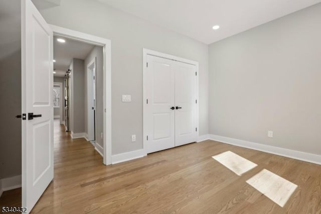 unfurnished bedroom featuring baseboards, a closet, recessed lighting, and light wood-style floors