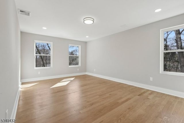 empty room featuring light wood-type flooring, baseboards, and a wealth of natural light