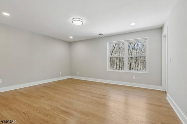 spare room featuring light wood-type flooring, visible vents, and baseboards