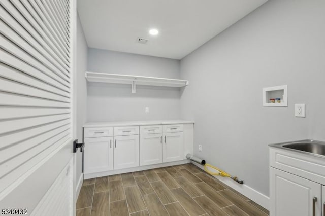 laundry room featuring cabinet space, visible vents, hookup for a washing machine, wood finish floors, and a sink